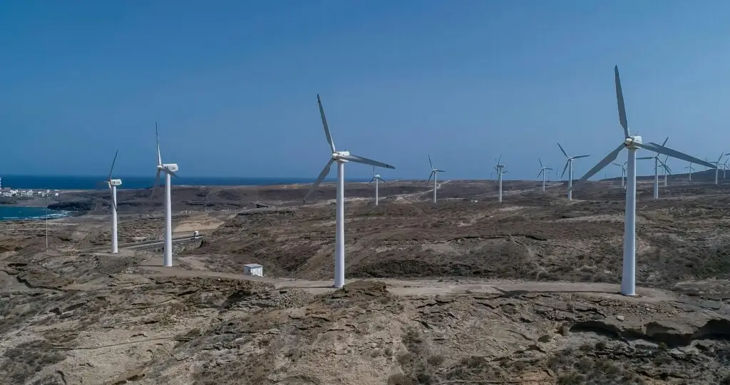 Wind turbines on a barren coast, harnessing renewable energy under a clear blue sky.
