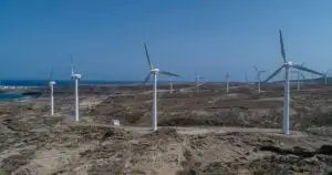 Wind turbines on a barren coast, harnessing renewable energy under a clear blue sky.