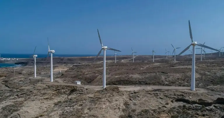 Wind turbines on a barren coast, harnessing renewable energy under a clear blue sky.